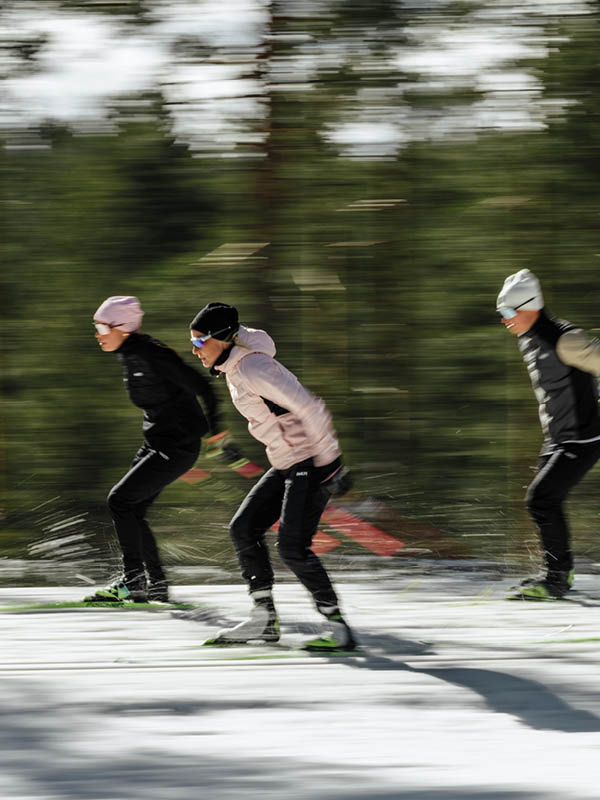 En person klädd i en lila dräkt åker längdskidor i ett snöigt, dimmigt landskap. Det omgivande området är vitt och sikten är dålig på grund av den täta dimman.