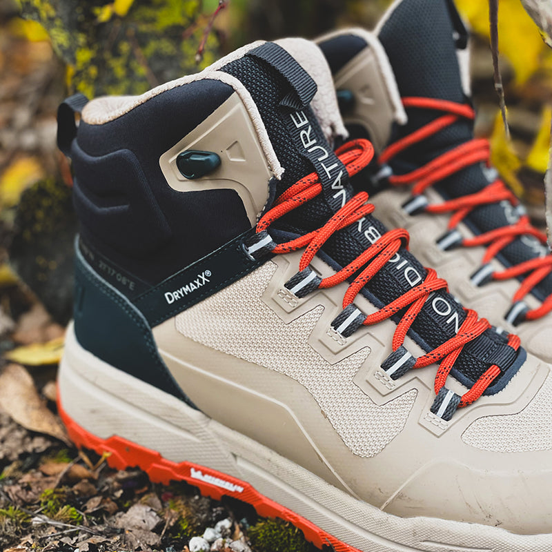 Närbild av Halti Hiker Kuru DrymaxX Outdoor Skor Dam med röda snören på lummig, stenig mark.