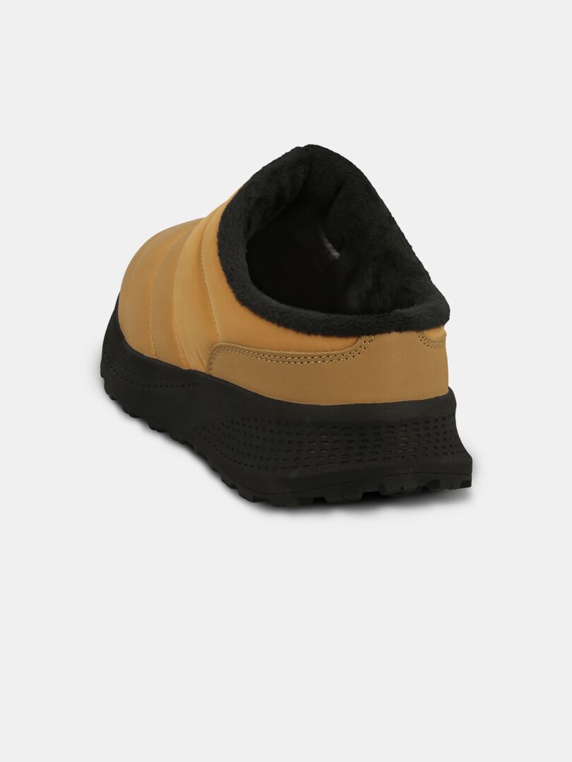 Baksidan av Halti Rest 2 Tofflor: beige slip-on, svart EVA-sula, mjukt foder, sandalkänsla, enfärgad bakgrund.