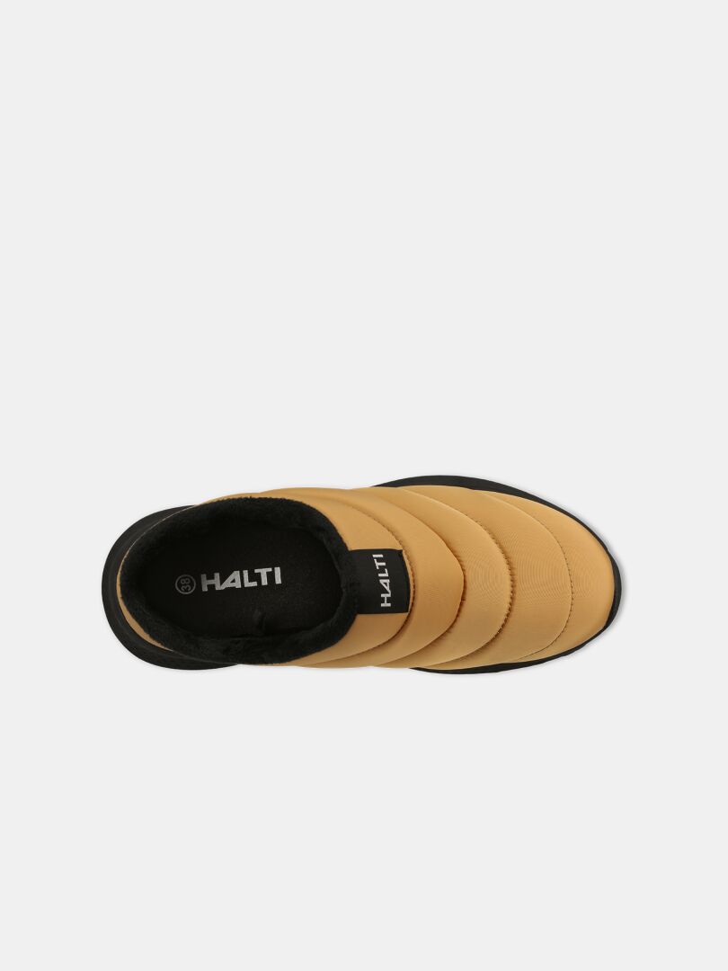 Ovanifrån-bild av Halti Rest 2 Tofflor: beige slip-on-sko med svart kant, EVA-sula, HALTI-logotyp på innersulan, mot vit bakgrund.