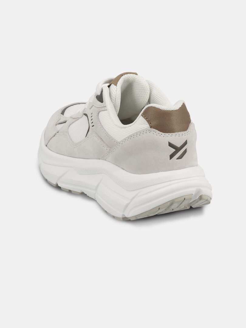 Halti Tove Sneaker Dam i vitt och beige, sedd bakifrån vänster, har en mörk pil-logotyp på hälen.