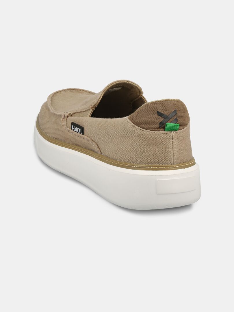Halti Lido Canvas Skor Herr är en brun slip-on med vit sula, svart tagg och grönsvart dragflik i hälen.
