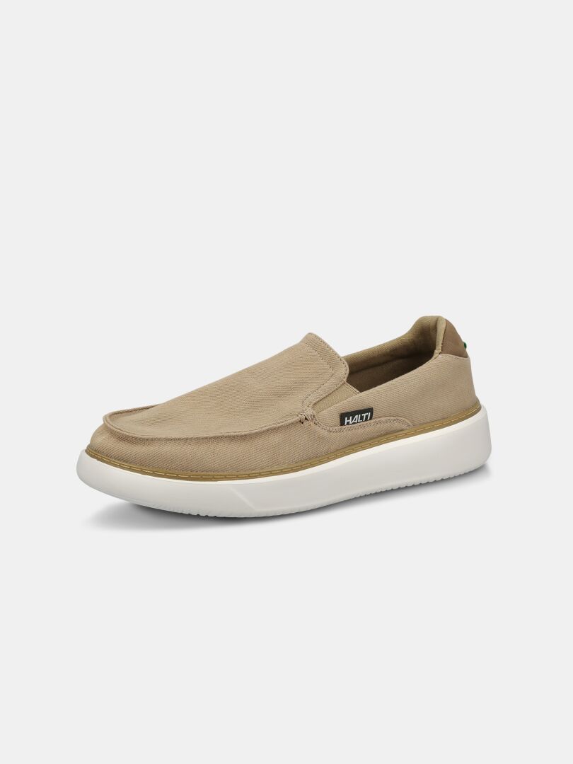 Halti Lido Canvas Skor Herr: Beige slip-on med vit sula och liten svart Halti-tag på sidan.