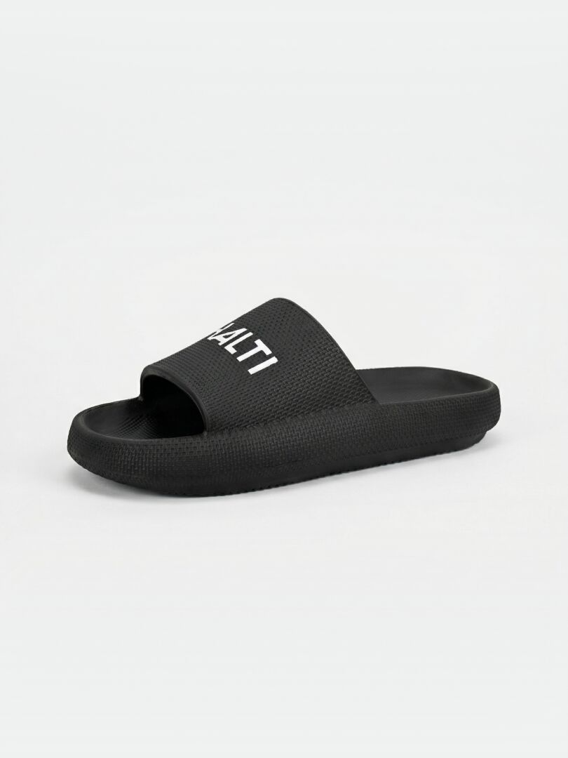 Halti Eazy 2 Sandal i svart EVA har en strukturerad sula och vit HALTI på remmen, som visas mot en enfärgad bakgrund.