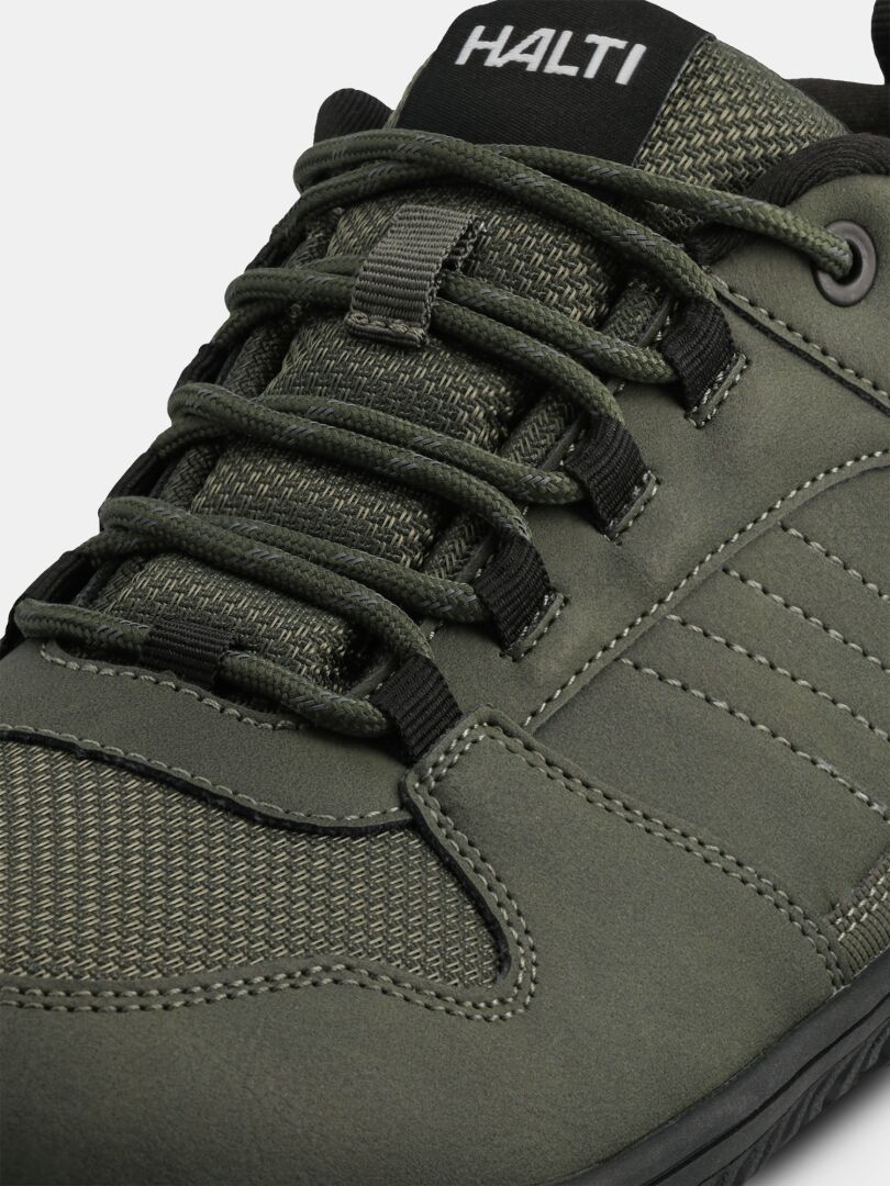 Närbild på de gröna Halti Tuntuma DX Barfotaskor Herr-sneakersen som visar skosnören, sömmar och logotypen på tungan.