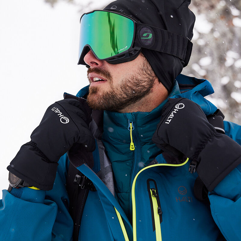 Man i Halti Alpine Unisex 3L DrymaxX Skaljacka och skidglasögon står utanför, redo för offpiståkning.