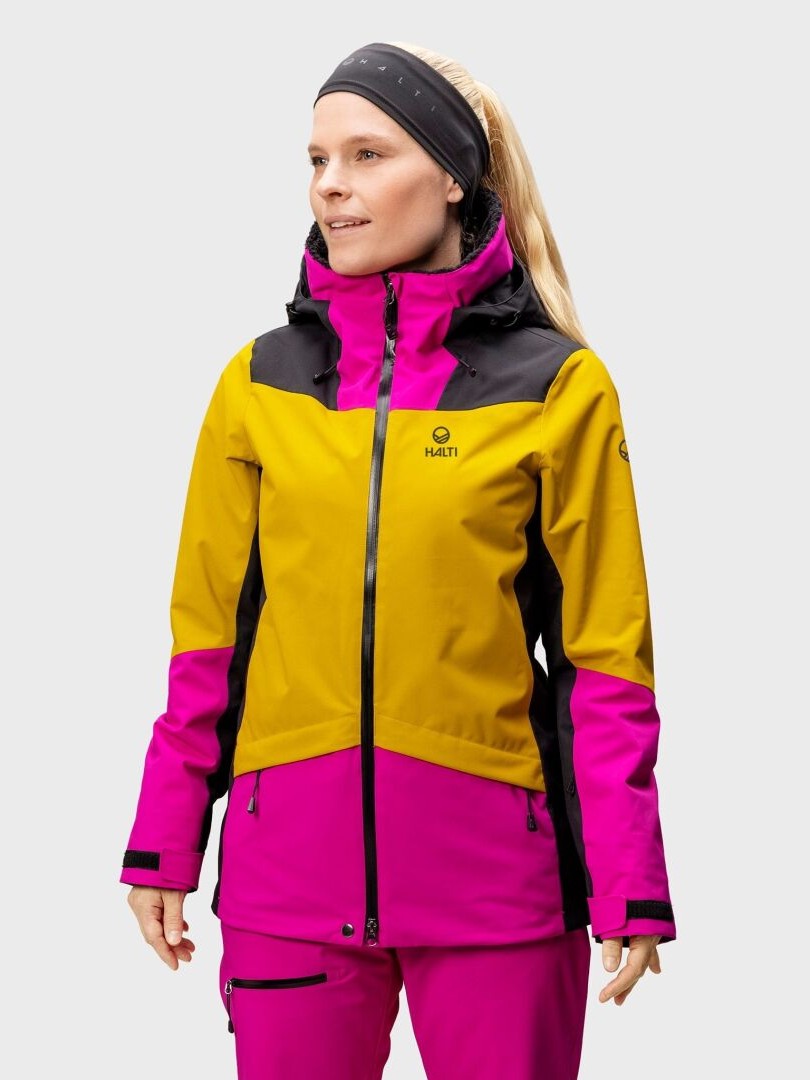 En kvinna i en Halti Planker DrymaxX Skidjacka Dam av återvunnet polyester tittar framåt mot en enfärgad bakgrund.
