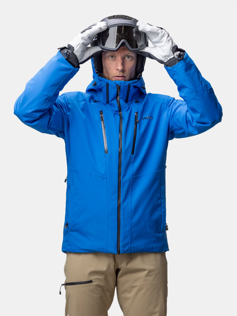 En man i en Halti Vertica DX skidjacka herr med Primaloft-vaddering sätter på sig skidglasögon, vänd mot kameran.