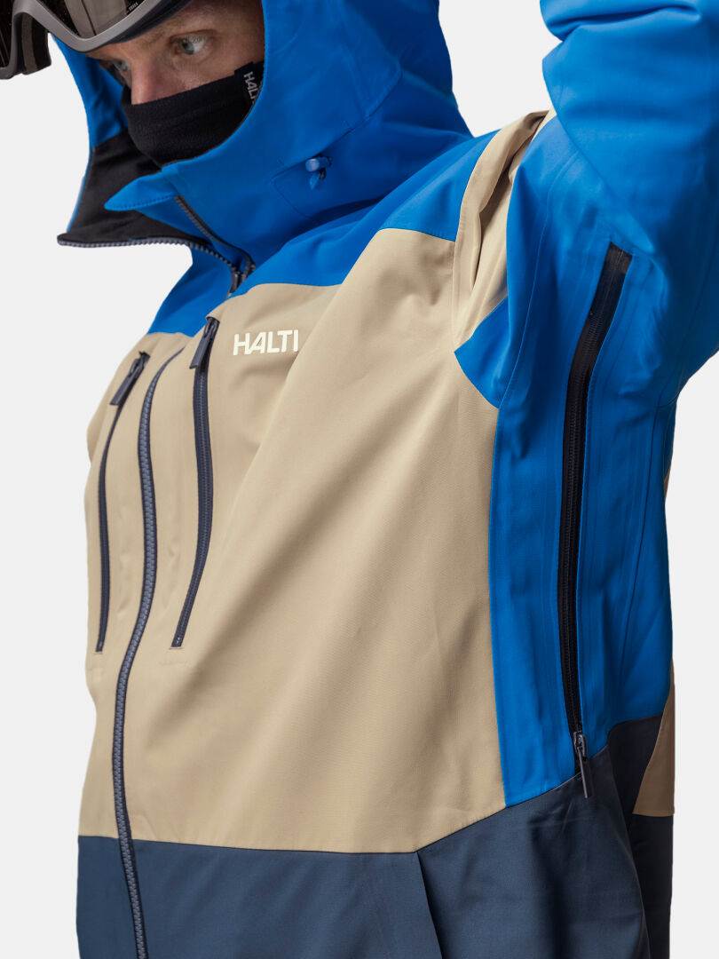 En blå och beige Halti Rizle Unisex 3L DX Skidjacka med ventilationsöppningar med dragkedja under armarna.