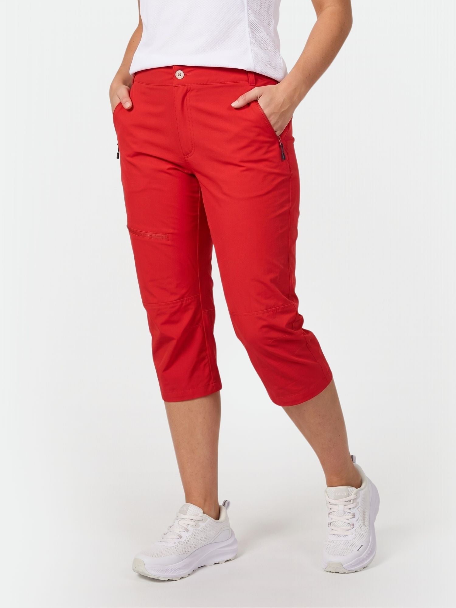 Person iklädd Halti Pallas Plus Dam X-stretch Lite Capribyxor, vit topp och sneakers mot en vit bakgrund.