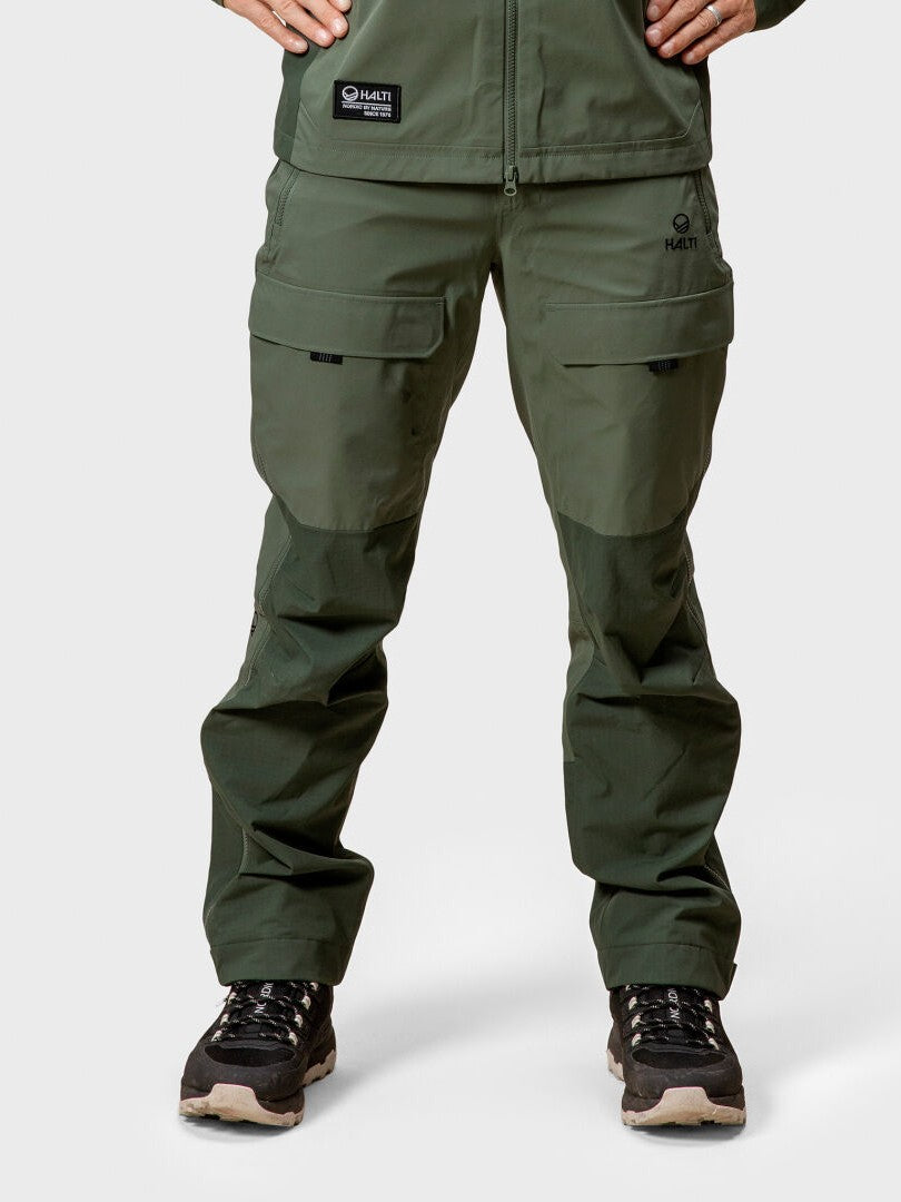 Person i Halti Hiker DrymaxX 3L Ventilated Byxor Herr och svarta vandringsskor, stående med händerna på höfterna.