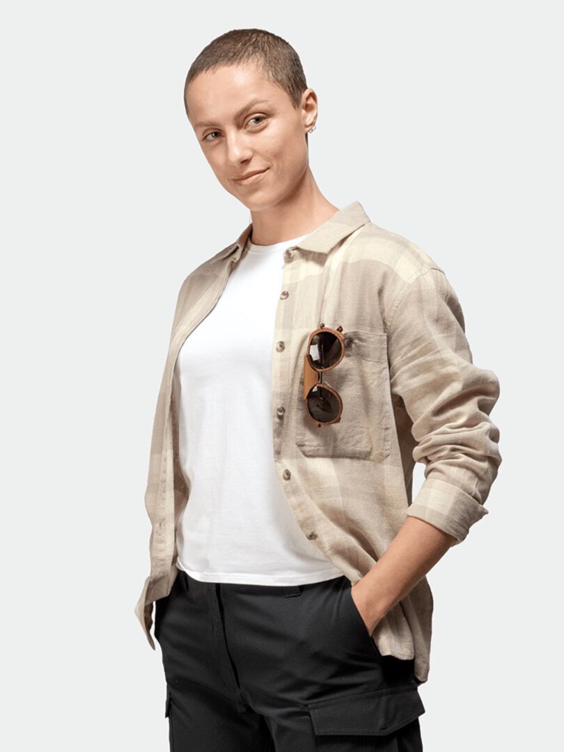 Kvinna med kort hår bär Halti Hiker Skjorta Dam över en vit t-shirt, solglasögon i fickan och händerna redo för vandring.
