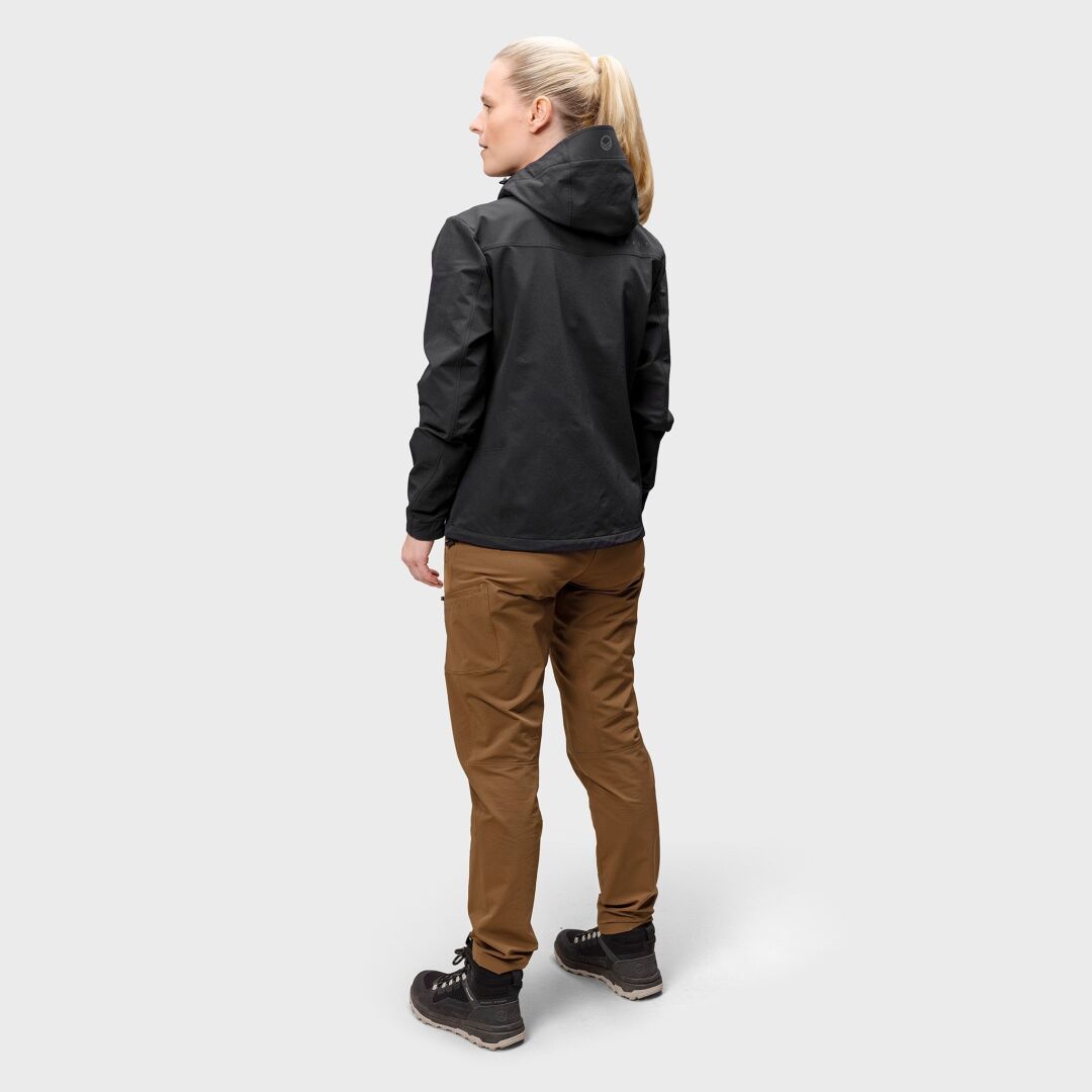 En person vetter bort i en svart luvjacka och Halti Pallas Evo Brushed X-stretch Byxor Dam mot en enfärgad bakgrund.