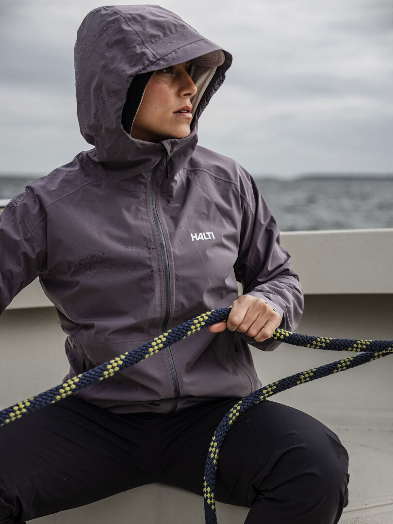 Person i Halti Pisarat 2,5L DX Skaljacka Dam håller ett rep på en båt med vatten i bakgrunden.