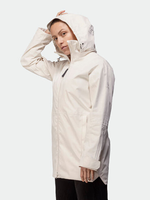 Kvinna i en lång, lätt Kallas DX Parka Dam från Halti, vänd åt sidan och justerar huvan för prestanda.