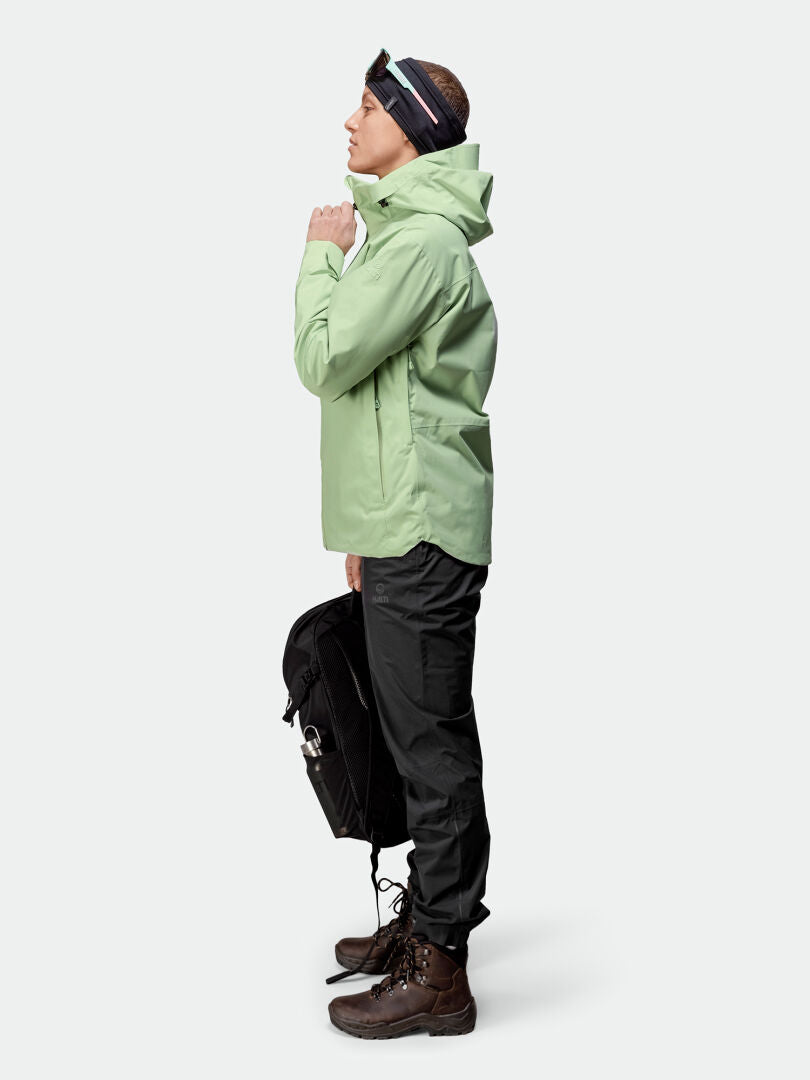 Person i Halti Staala DX Skaljacka Dam, svarta byxor, bruna boots och svart ryggsäck står i profil.