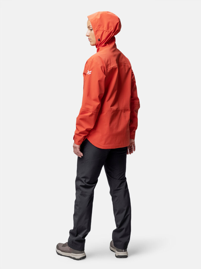 Person i orange Halti Staala DX Skaljacka Dam, svarta byxor och bruna skor, vänd något bortåt.