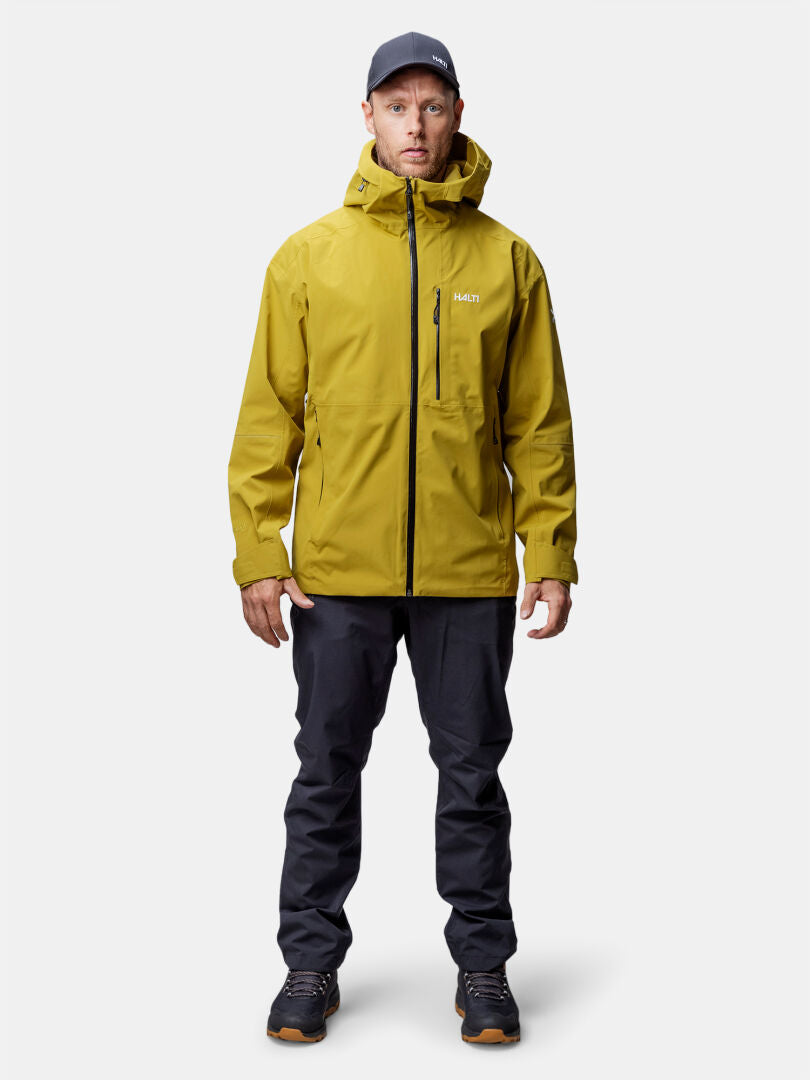 En man bär Halti Staala DX Skaljacka Herr, mörka byxor, svarta skor och en mörk keps-perfekt för vandring.