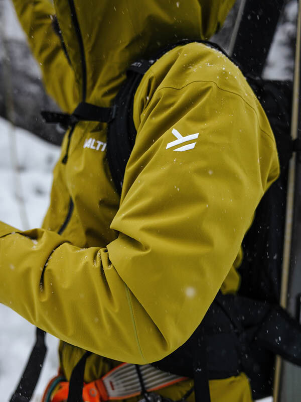 Person i Halti Staala DX Skaljacka Herr bär utrustning utomhus under vattenavvisande vandring i snö.