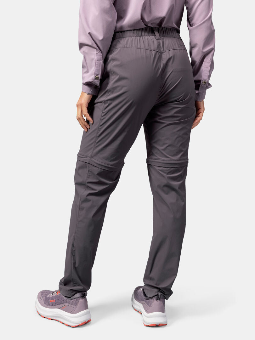 Kvinna klädd i Halti Pallas Cool Stretch Zip-off Byxor, lavendelfärgad topp och lila sneakers, bakifrån.
