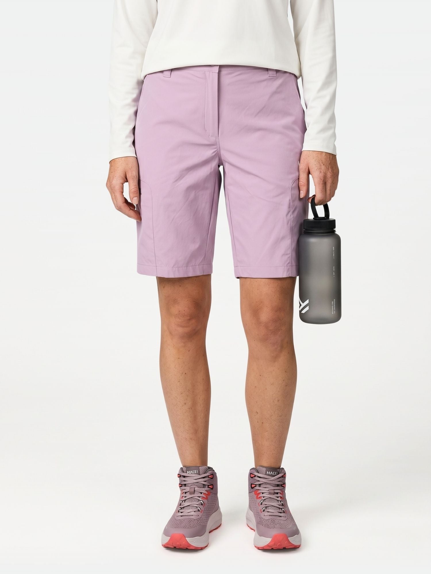 Person klädd i Halti Pallas Cool Shorts Dam i lavendel, vit långärmad topp, rosa sneakers och grå vattenflaska.