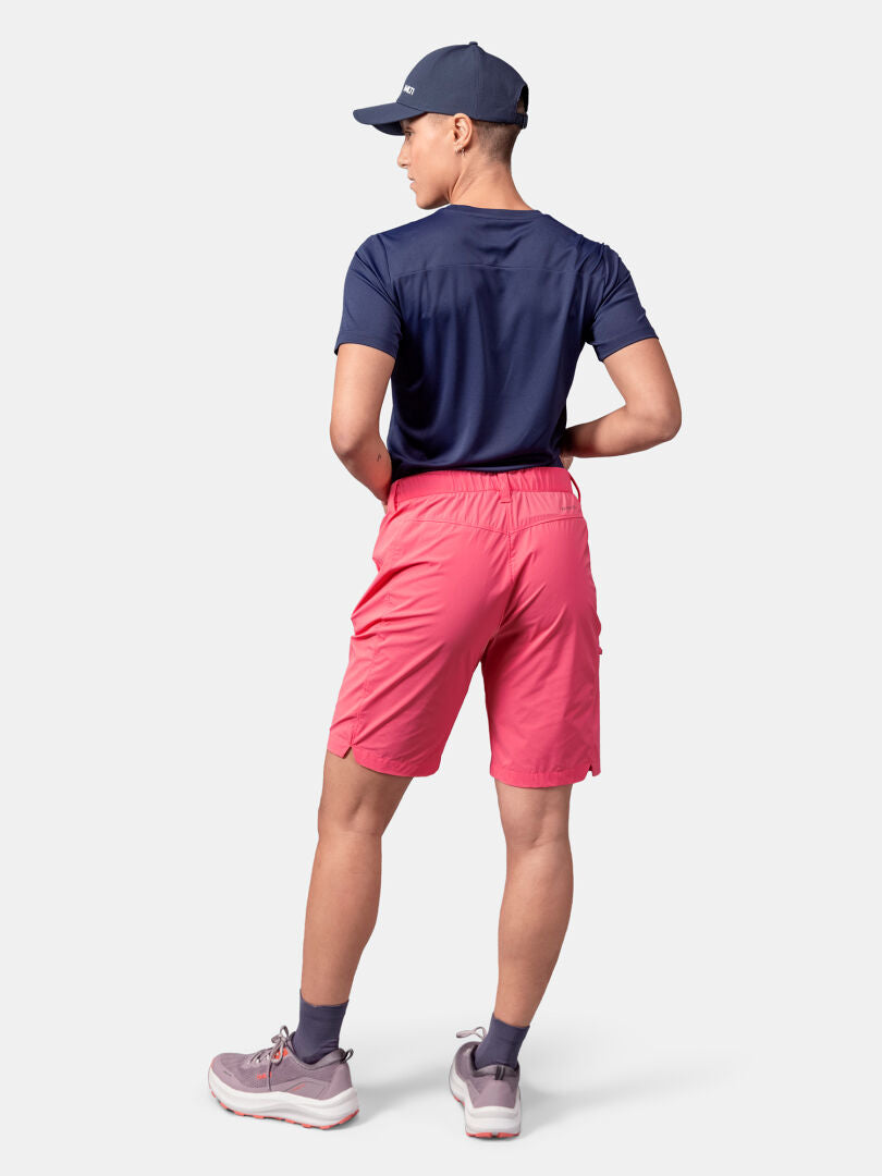Person vänd bort, klädd i marinblå keps och skjorta, Halti Pallas Cool Shorts Dam i rosa och grå sneakers med strumpor.