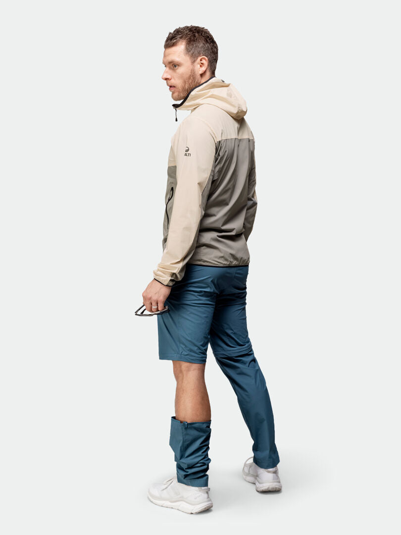 Man står snett i Halti Pallas Cool X-stretch Jacka Herr, UPF 90+, blå shorts, blå damasker, med solglasögon.