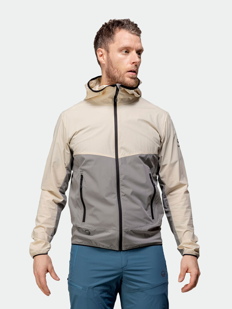 En man i en Halti Pallas Cool X-stretch jacka med snabba egenskaper och blå byxor står vänd åt vänster.