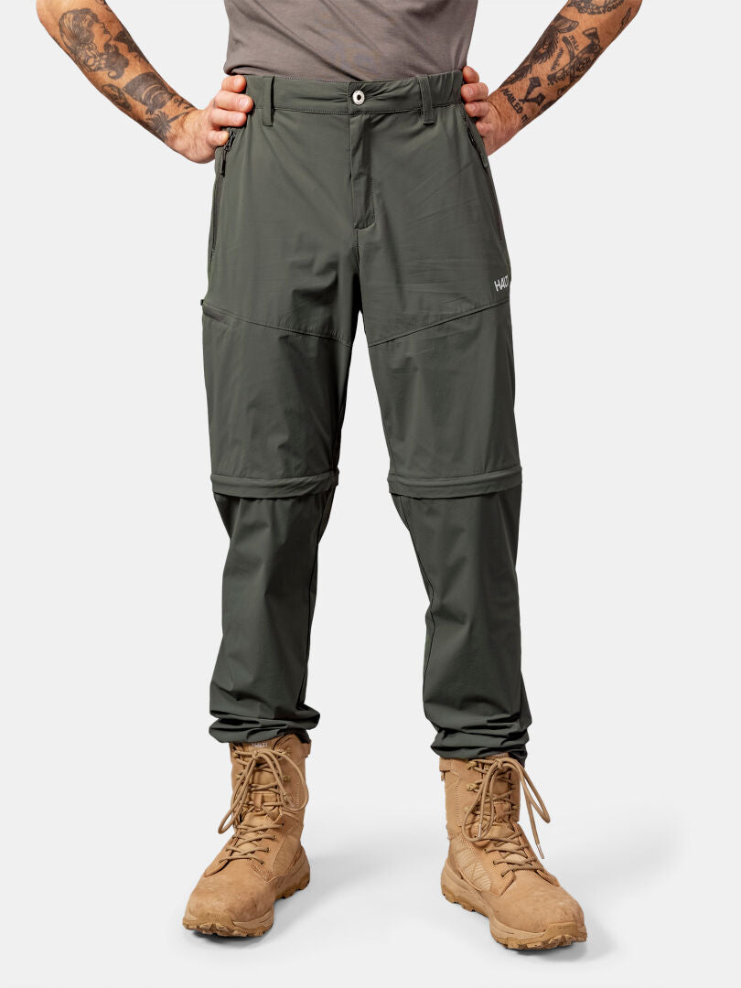 Person klädd i Halti Pallas Cool Stretch Zip-off Byxor Herr och bruna snörstövlar, visad från axlarna och nedåt.