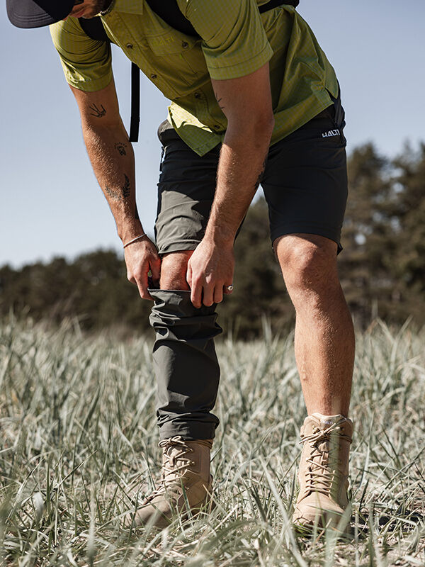 Utomhus bär en person i grön skjorta och bruna stövlar Halti Pallas Cool Stretch Zip-off Byxor Herr över shorts.