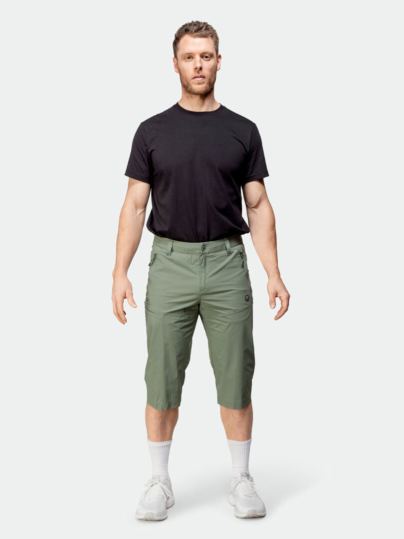 En man vetter framåt i en svart snabbtorkande t-shirt, Halti Pallas Cool X-stretch capribyxor, vita strumpor och sneakers.