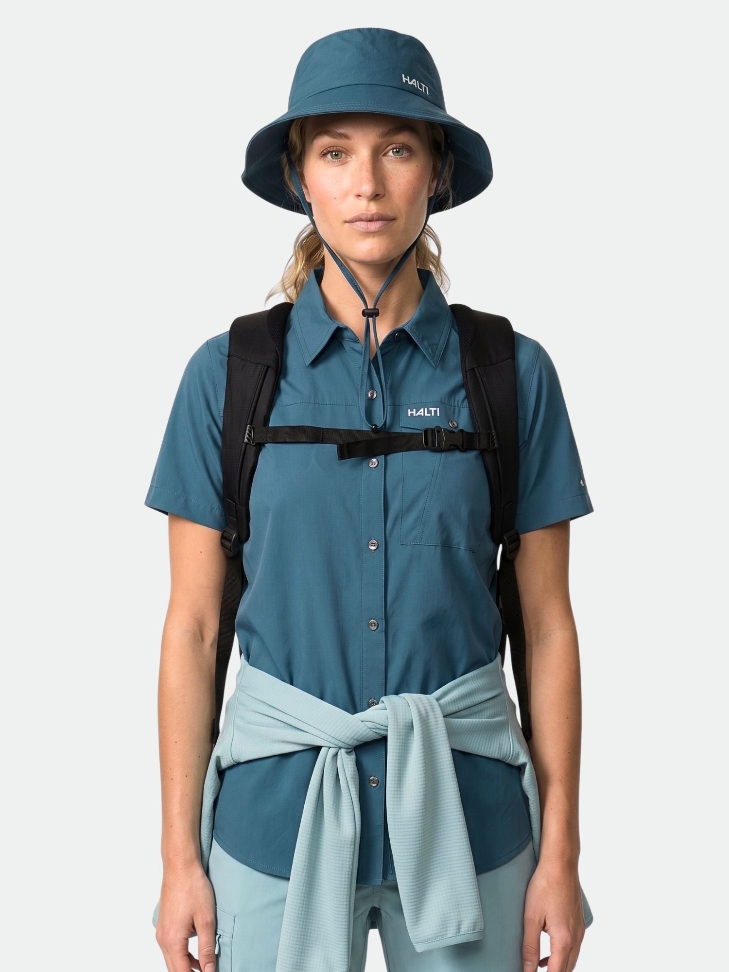 En person i blå bucket hat och Halti Samoy Funktionsskjorta Dam, med ryggsäck på, vänd framåt.