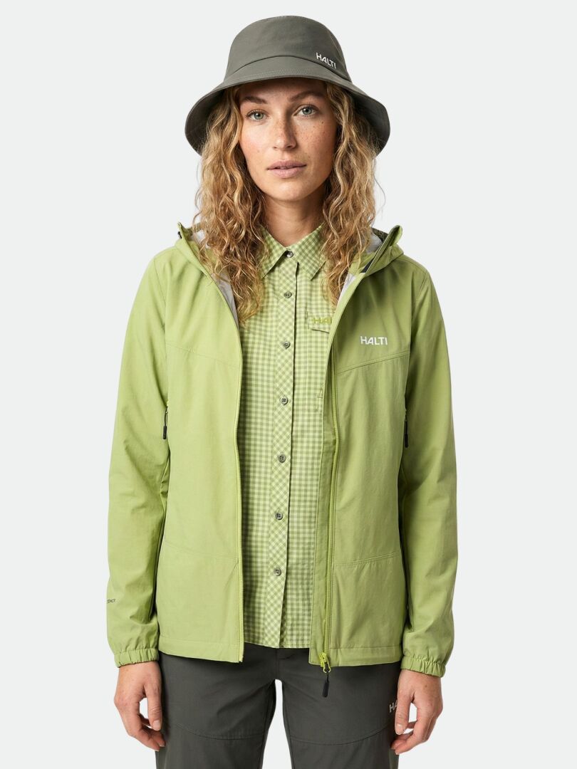 En kvinna bär Halti Pallas Evo X-stretch Jacka Dam, en grönrutig skjorta och en grå bucket hat.