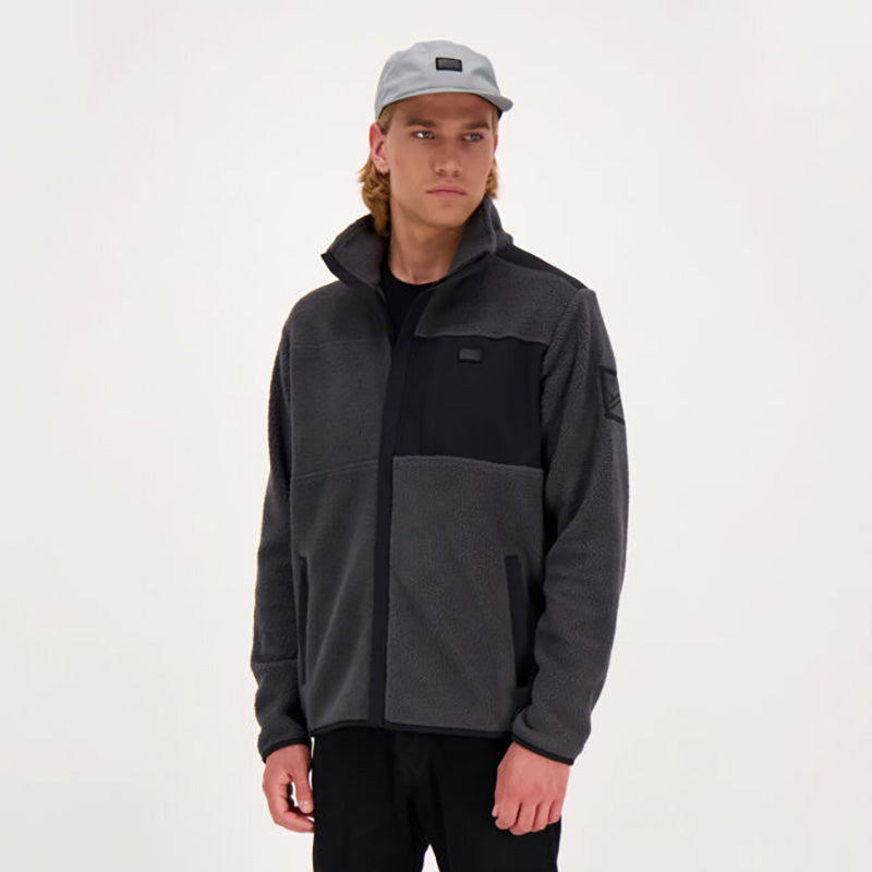 En person bär en grå mössa och en Halti Klaidu Herr Fleecejacka tillverkad av återvunnen polyester, mot en enfärgad bakgrund.