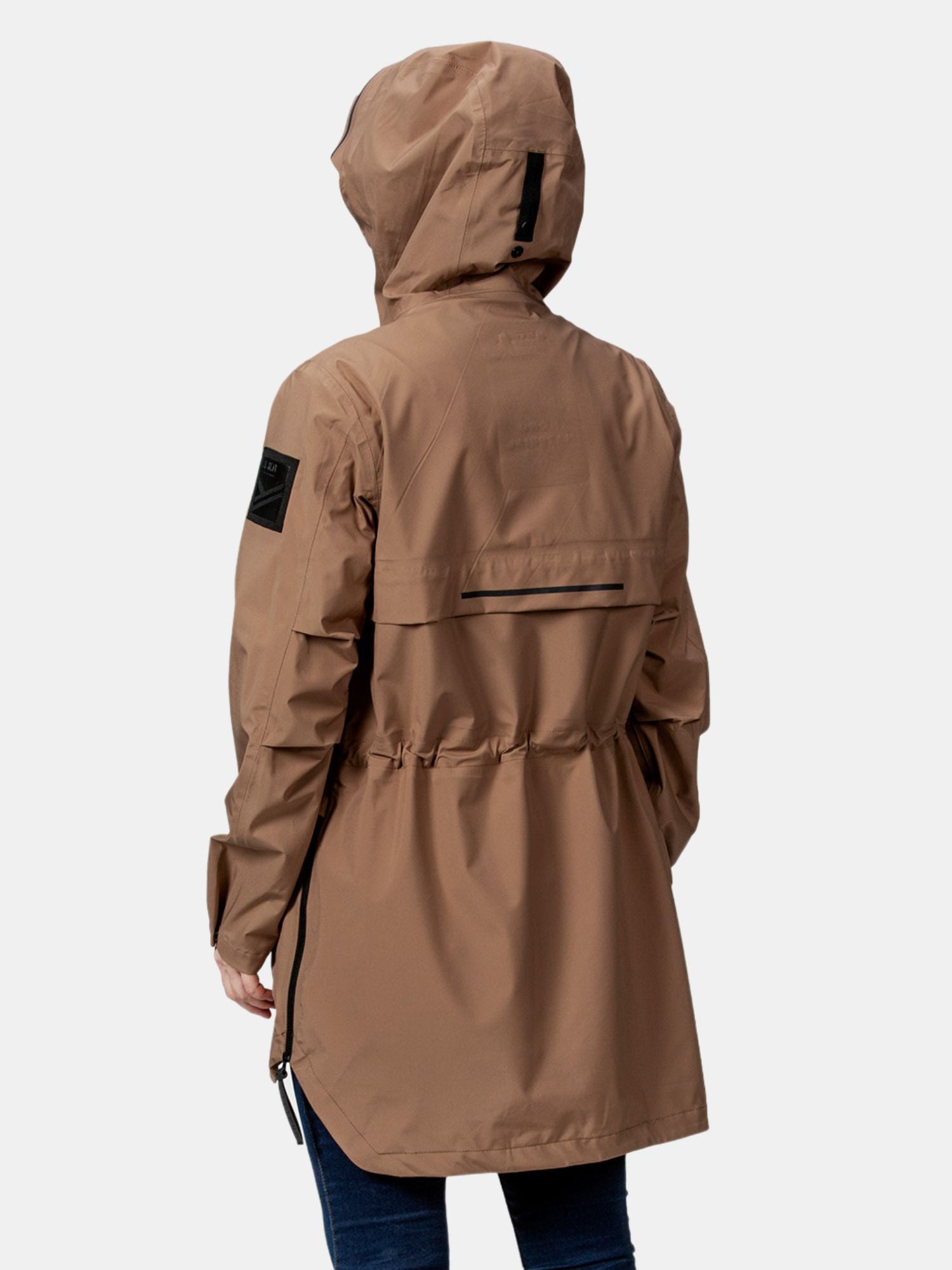 En person i en brun Halti Kurvi DrymaxX 3L Parka Jacka Dam, sedd bakifrån, med mörka byxor och armar längs sidorna.