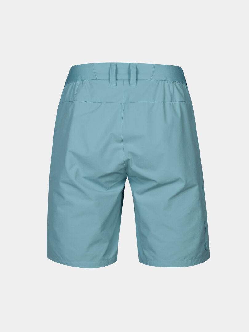 Bakifrån Halti Drive X-stretch Shorts Dam i ljusblått med bälteshällor och elastisk midja, på enfärgad bakgrund.