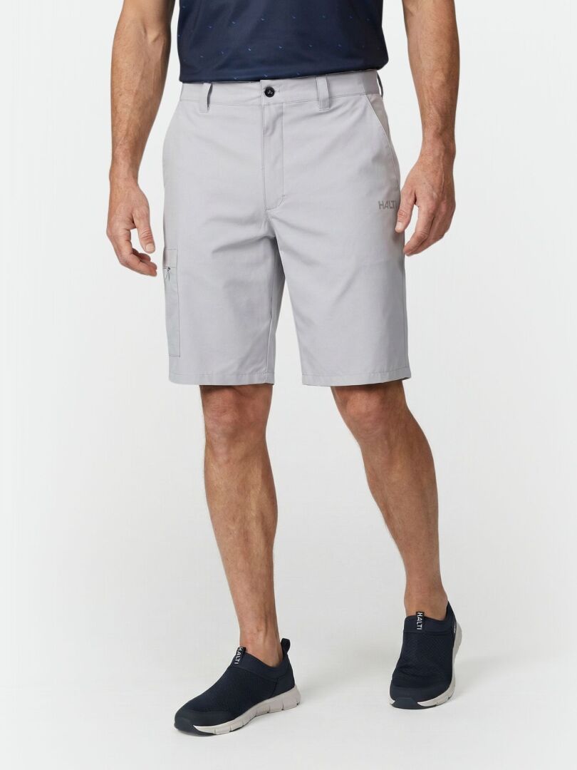 En man bär Halti Drive X-stretch Shorts - perfekta för varma sommardagar - med en marinblå skjorta och svarta slip-on-skor.
