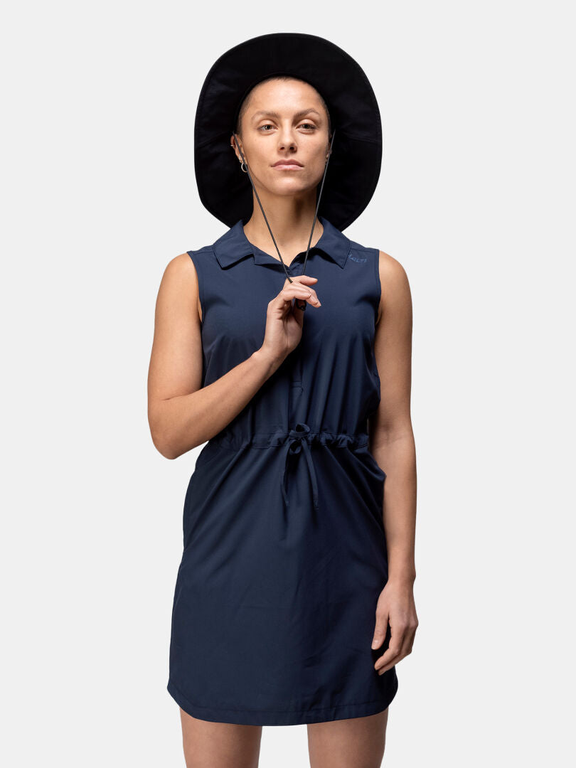 En person i Halti Chipper X-stretch Klänning Dam och svart hatt står mot en ljus bakgrund.