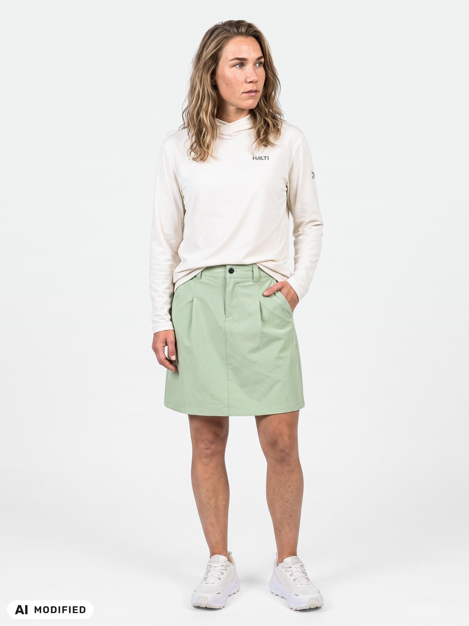 Person klädd i en ljus långärmad tröja, Halti Drive X-stretch Kjol Dam i ljusgrönt och vita sneakers.