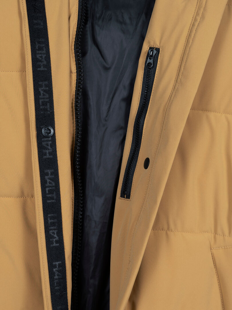 Närbild på Halti Brahe Puffer Long Vinterjacka Dam i beige med svart dragkedja, kantband och återvunnen polyester.