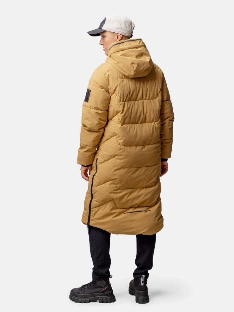 Person i Halti Brahe Puffer Long Vinterjacka för dam, svart byxa och ljus keps, sedd bakifrån.