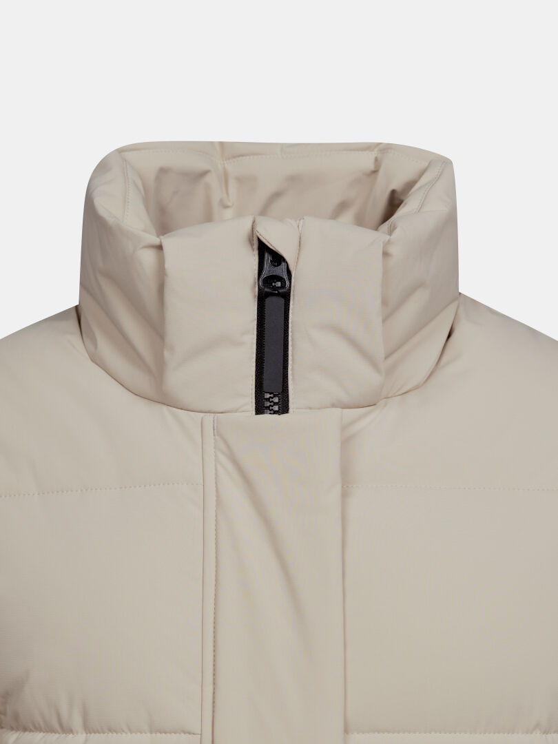 Närbild på Halti Brahe Puffer Long vinterjacka för dam i beige med hög krage och en kort svart dragkedja uppe i mitten.
