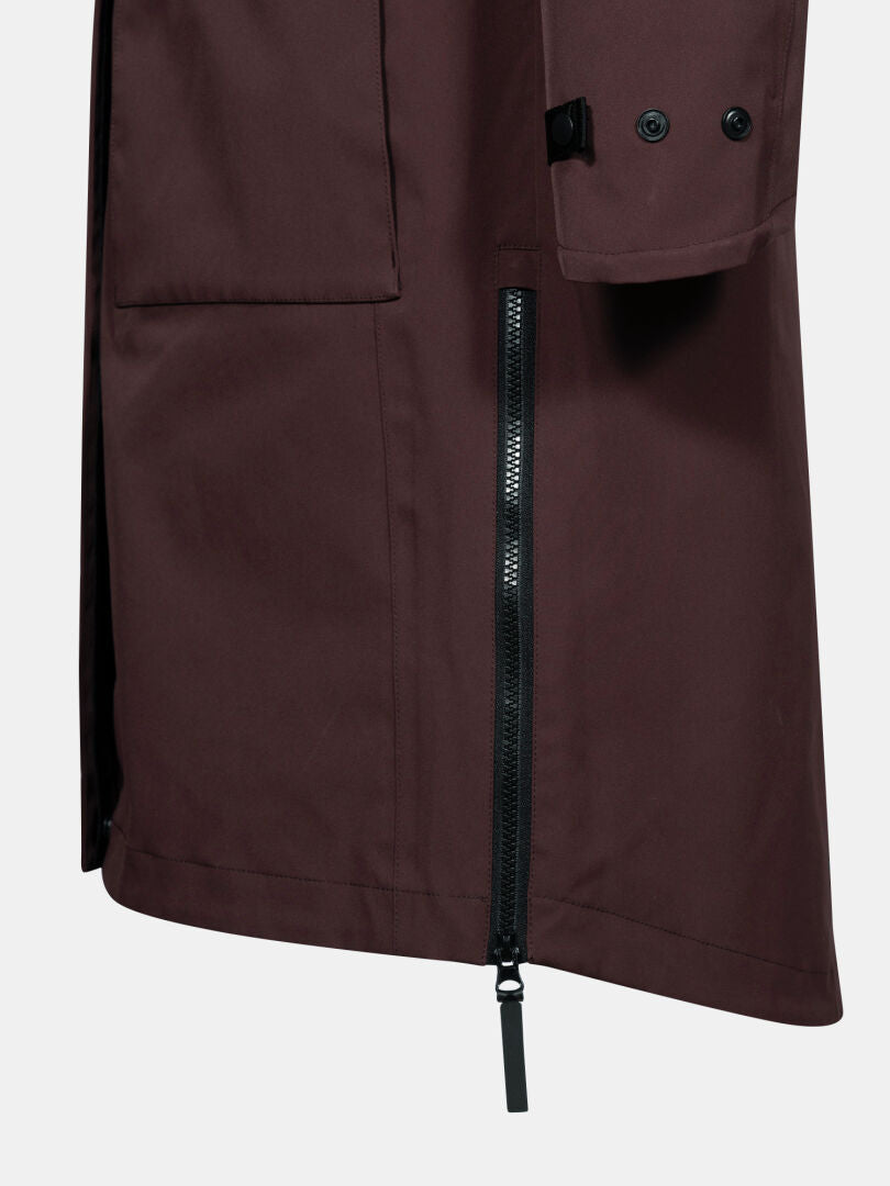 Närbild av Halti Tokoi II DX Parkajacka Dam i mörkbrun färg med svart dragkedja och stor ficka, på enfärgad bakgrund.