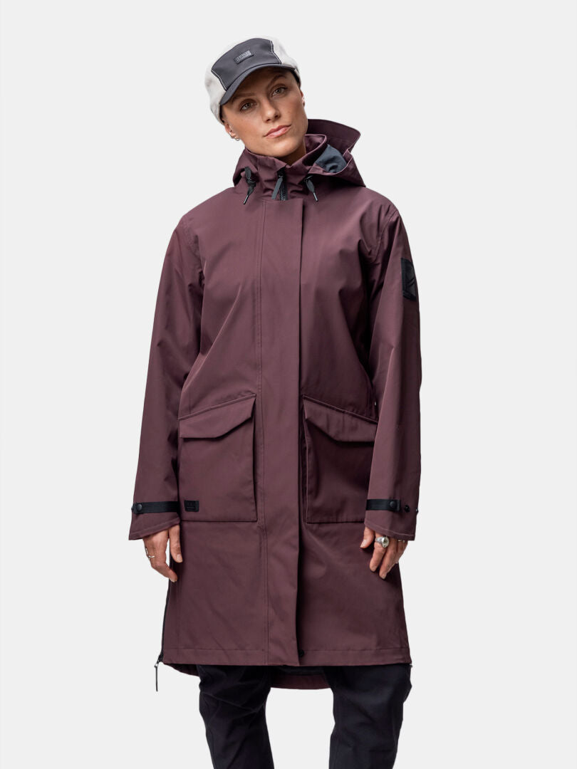 En kvinna bär Halti Tokoi II DX Parkajacka Dam, rödbrun, tillverkad av återvunnen polyester, mot en vit bakgrund.