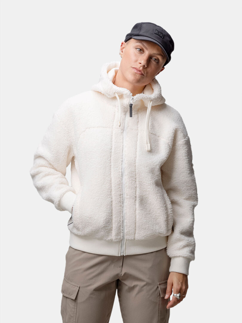 Modellen bär en Halti Lykky Fleece Jacka Dam, en grå keps och beige cargobyxor mot en enfärgad vit bakgrund.