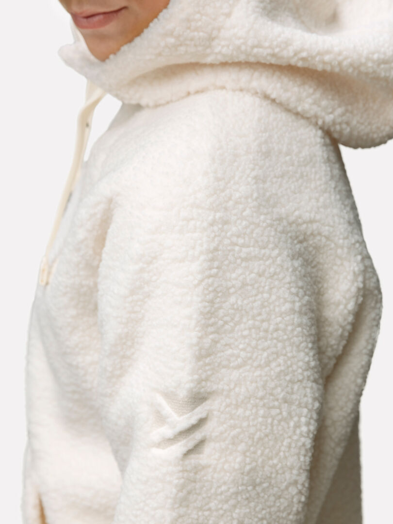 Person med en krämfärgad Halti Lykky Fleecetröjä Dam, vy från sidan, med liten logotyp på ärmen.