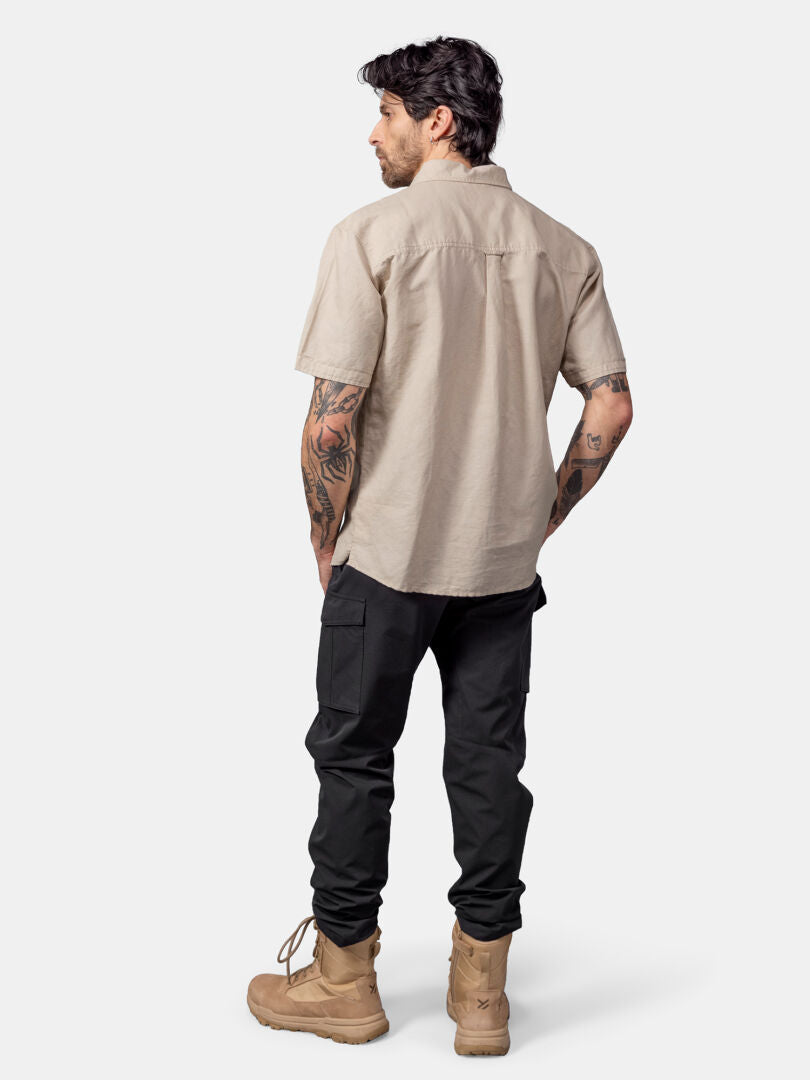 Man i beige Halti Notsgi Skjorta Herr, svarta byxor och solbruna stövlar, med ryggen mot kameran.