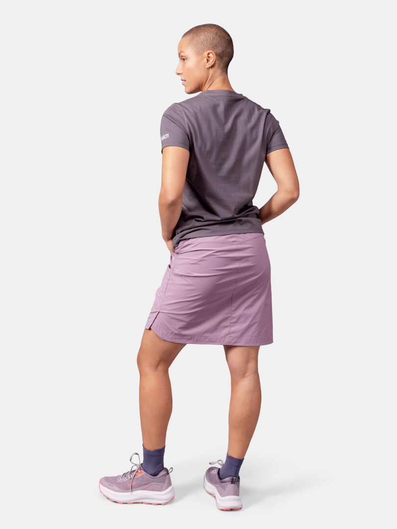 Person vänd bort, klädd i Halti Matka II T-skjorta Dam grå UPF 30+ t-shirt, lila kjol, lila strumpor, lila sneakers.