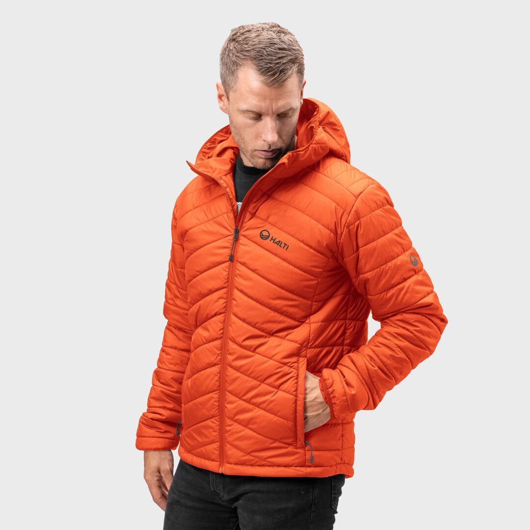 En man bär en Halti Komu Lätt Vadderad Jacka Herr med huva, stående mot en vanlig bakgrund.