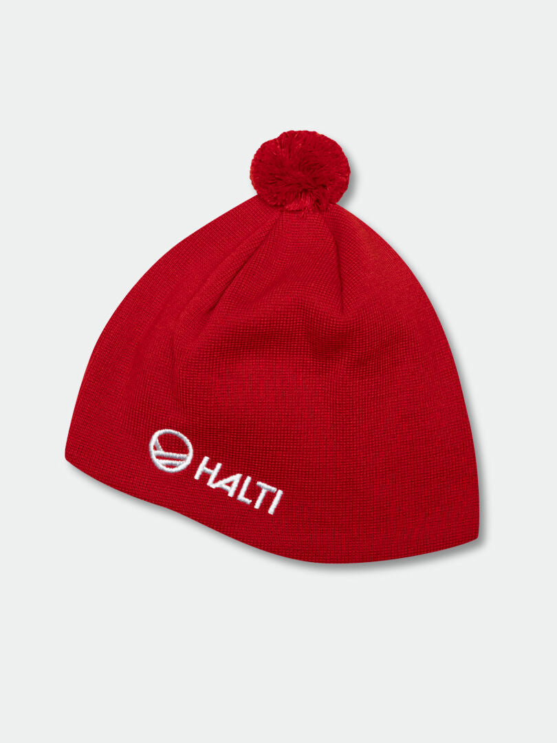 Halti Peesi Mössa är en röd stickad mössa i merinoull med en pom-pom och vit broderad Halti-logotyp framtill.